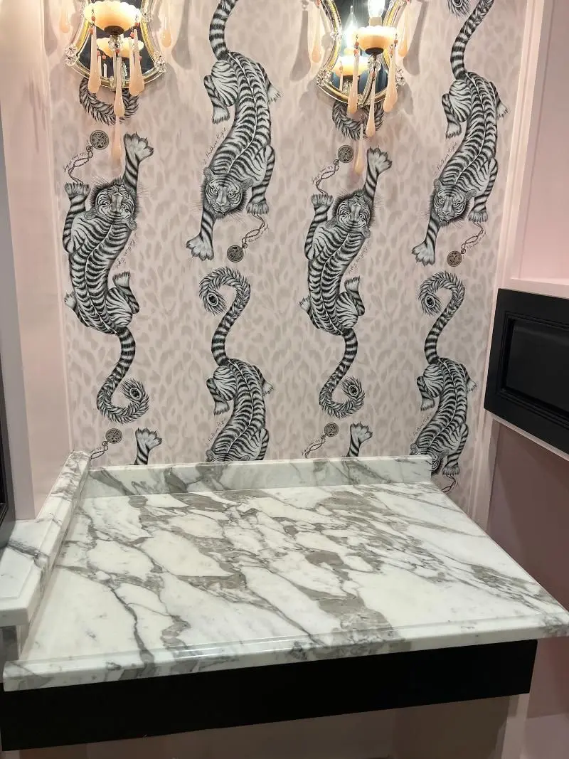Elegant marble vanity with designer tiger wallpaper and crystal sconces in luxury powder room Alvin TX