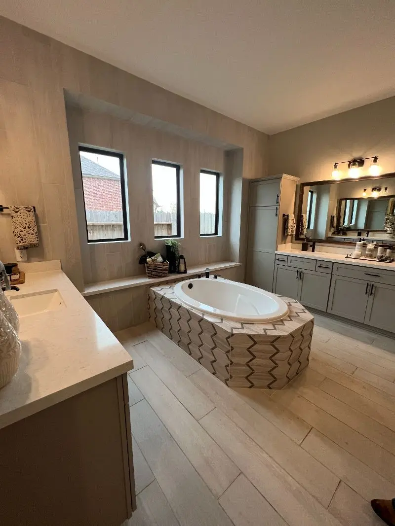 Spa master bathroom with freestanding soaking tub chevron tile surround and dual vanities in Alvin TX