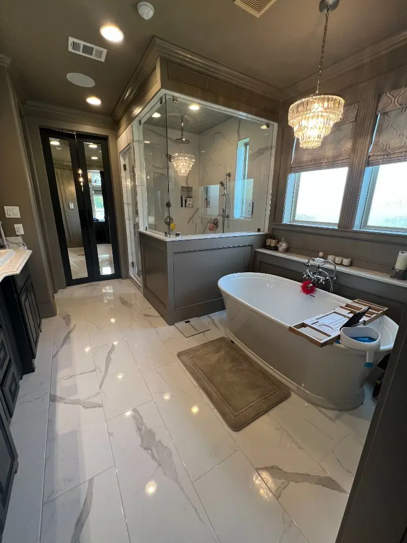 Luxury master bathroom with freestanding tub crystal chandelier marble floors and glass shower in Pearland TX