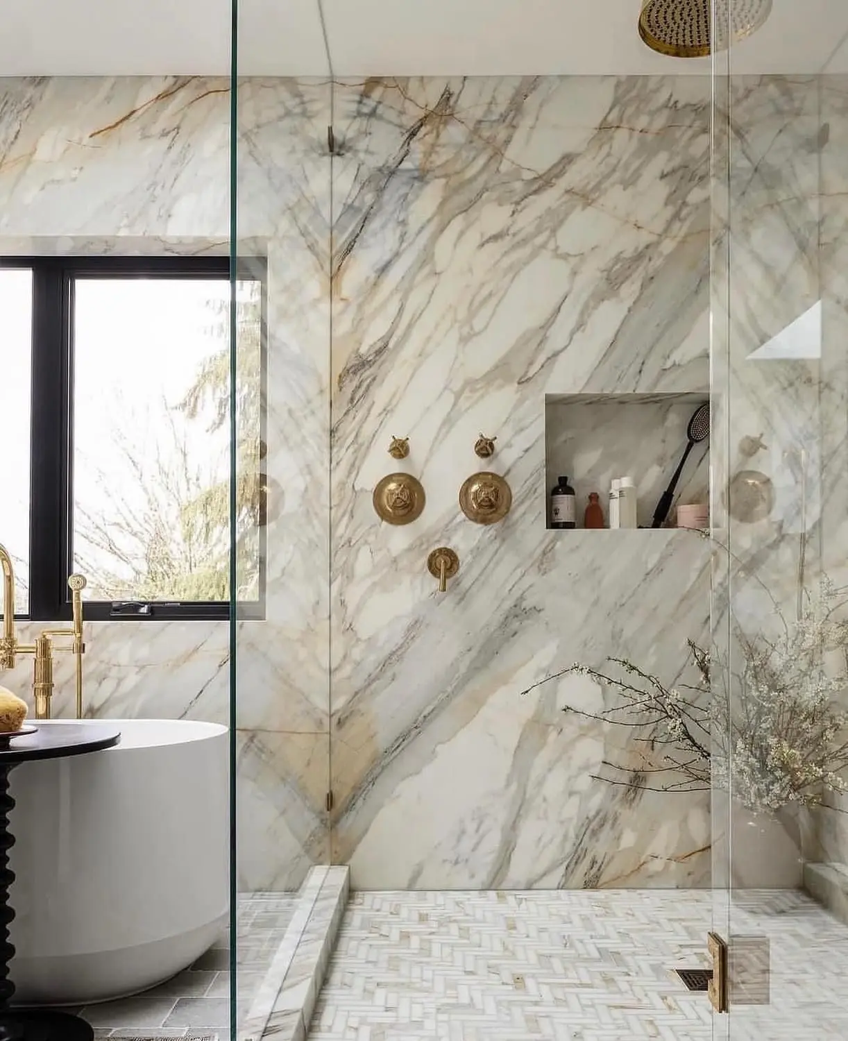 Luxury Calacatta marble shower with gold fixtures herringbone floor and freestanding tub in Alvin TX