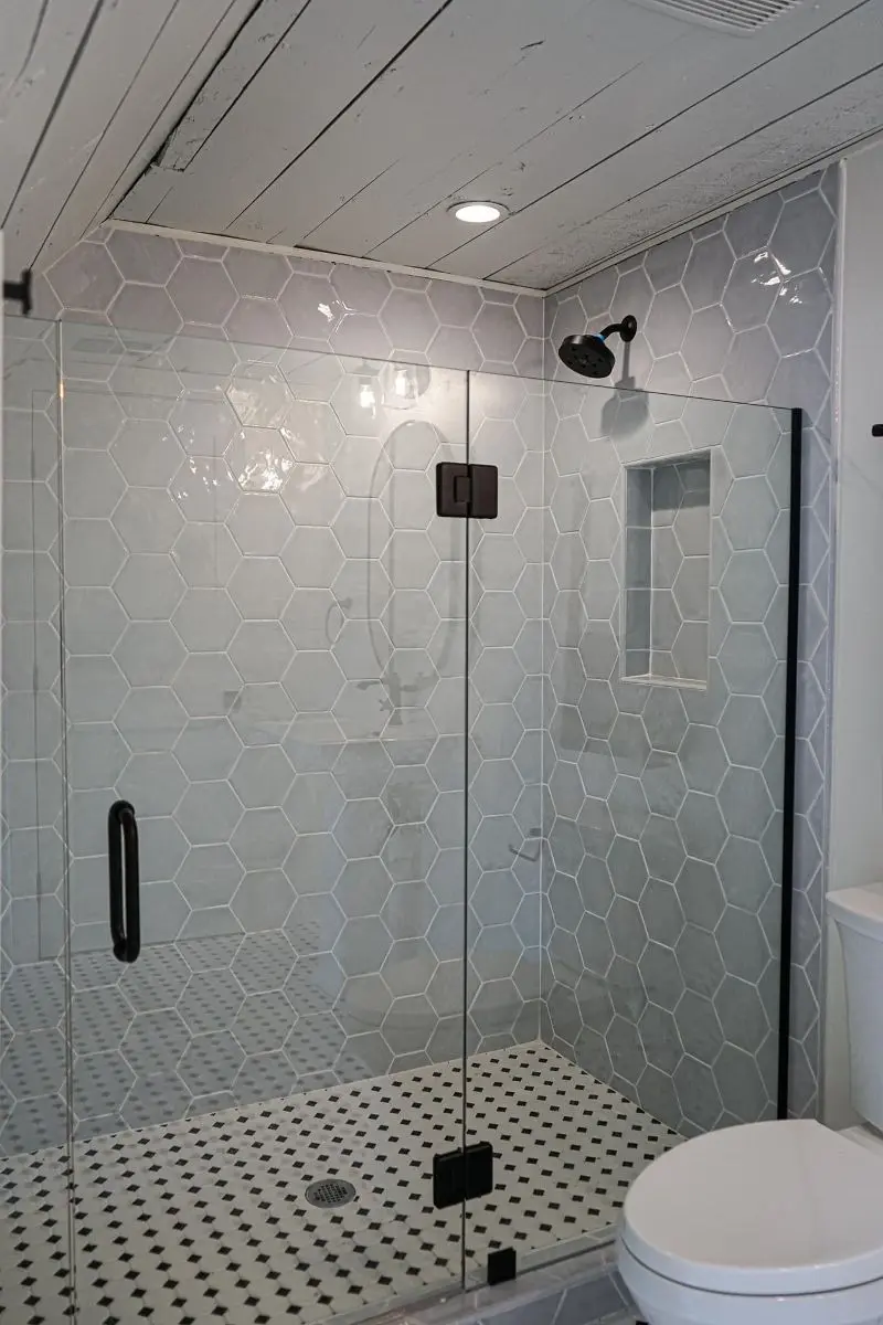 Large hexagon tile walk-in shower with glass enclosure and basketweave floor in Pearland TX
