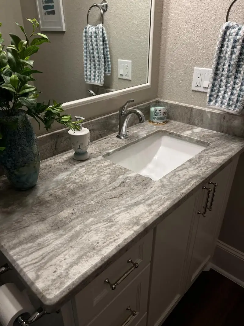 Gray marble vanity countertop with white cabinets and chrome fixtures in Friendswood TX bathroom