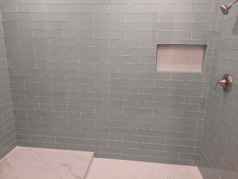Seafoam green subway tile shower with marble floor and built-in niche in Dickinson TX