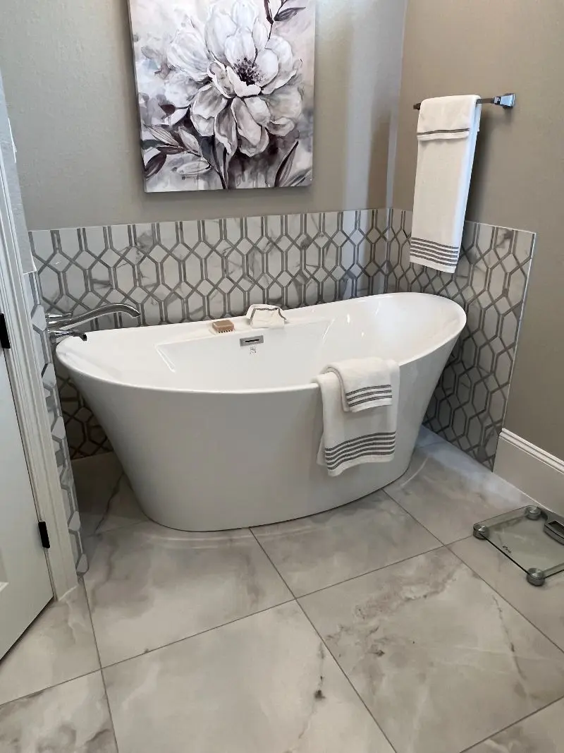 Freestanding soaking tub with geometric tile backsplash and marble floors in Santa Fe TX