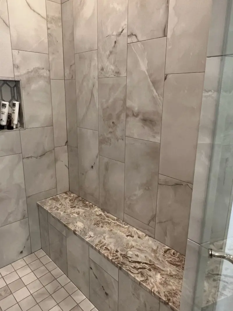 Marble look tile shower with exotic quartzite bench and glass enclosure in Pearland TX