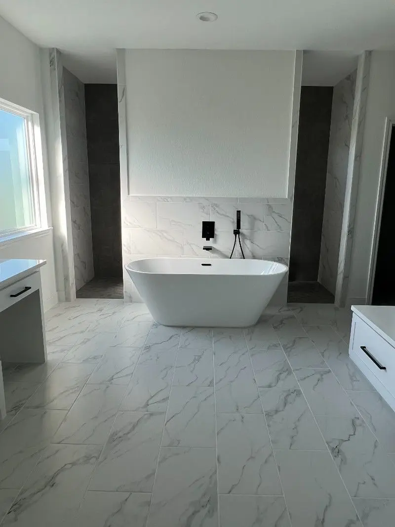 Modern master bathroom with freestanding tub marble tile dual walk-in showers and black fixtures in Dickinson TX