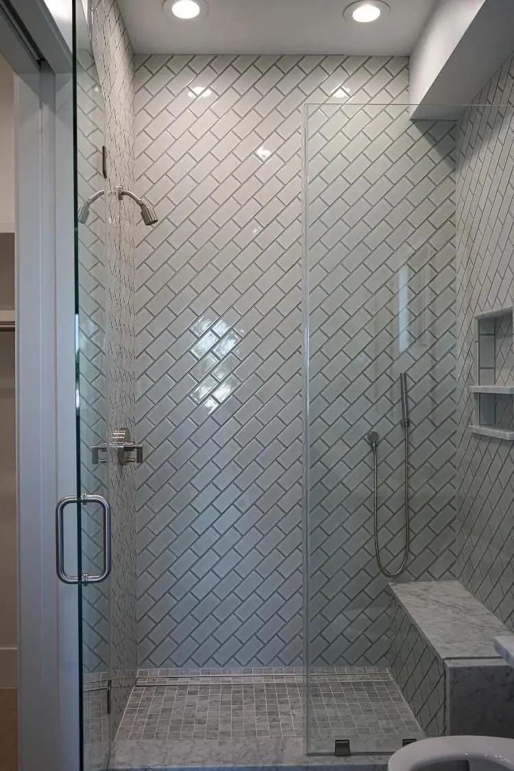 Herringbone subway tile walk-in shower with marble bench and frameless glass in Texas City