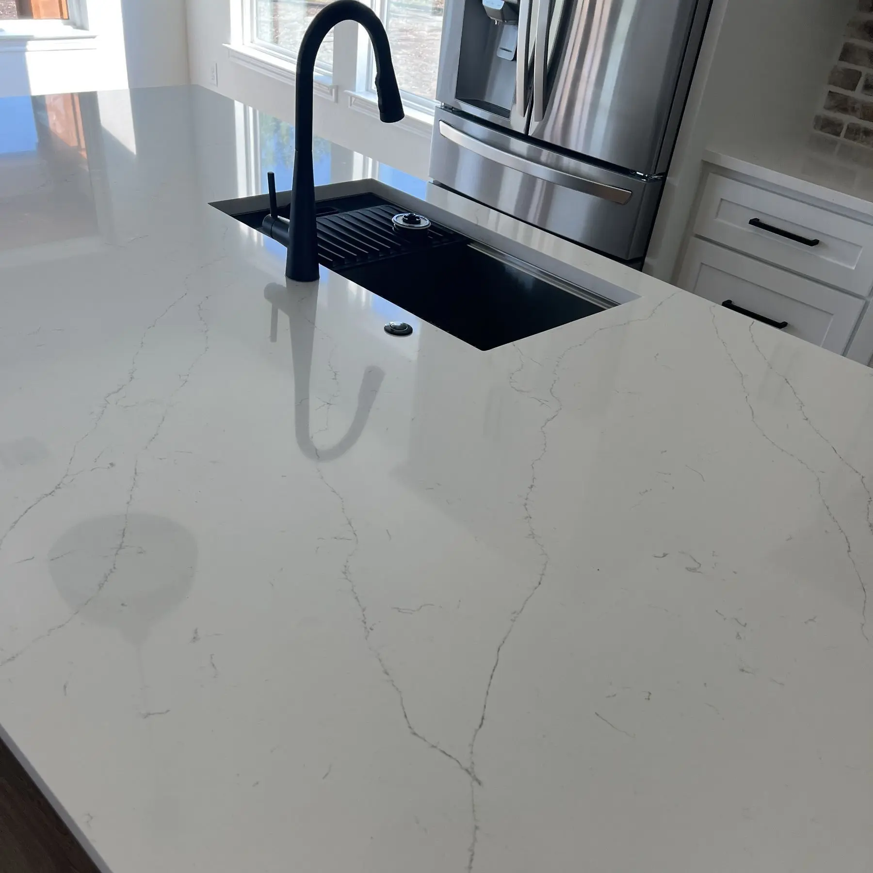 White quartz countertop with elegant veining and modern black sink in Alvin TX kitchen