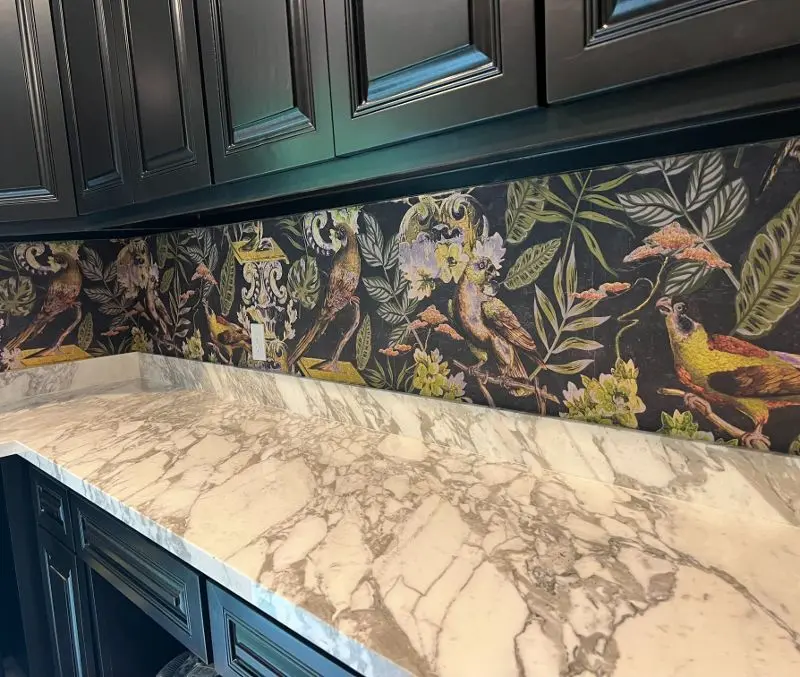Calacatta marble countertop with bold botanical wallpaper and dark teal cabinets in Santa Fe TX