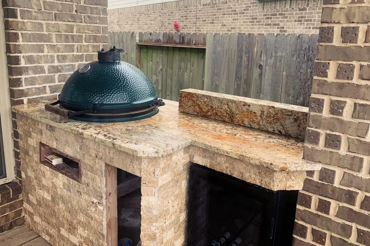 Outdoor kitchen with granite countertops Big Green Egg grill and brick surround in Pearland TX