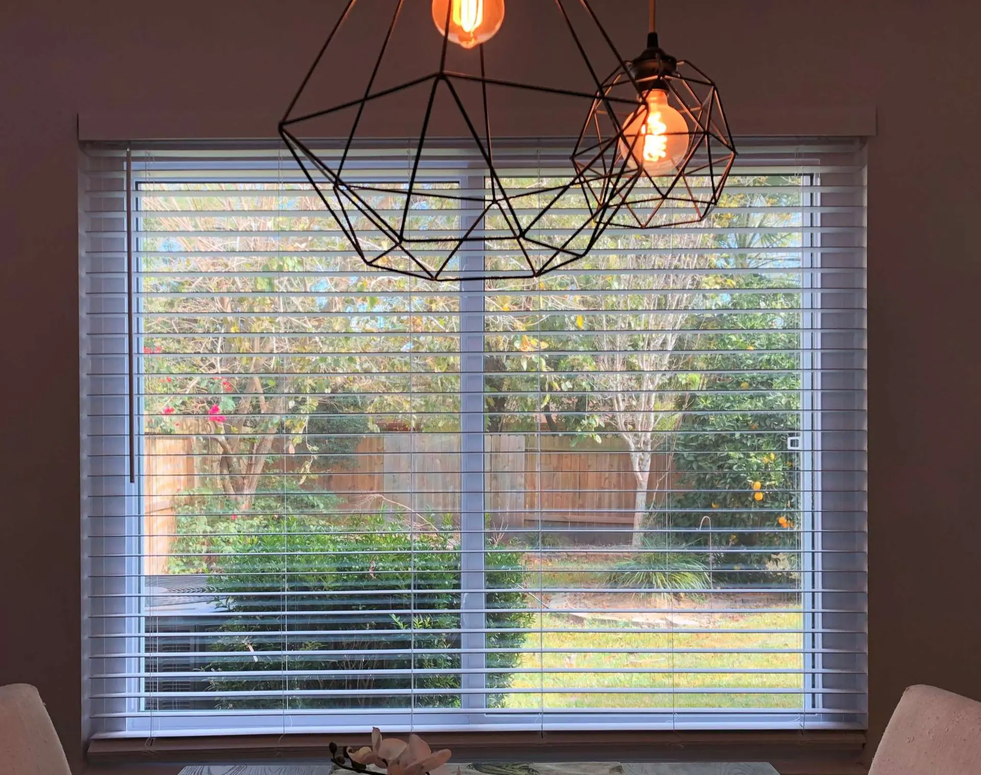Dining room with geometric pendant lights and garden view in Friendswood TX home