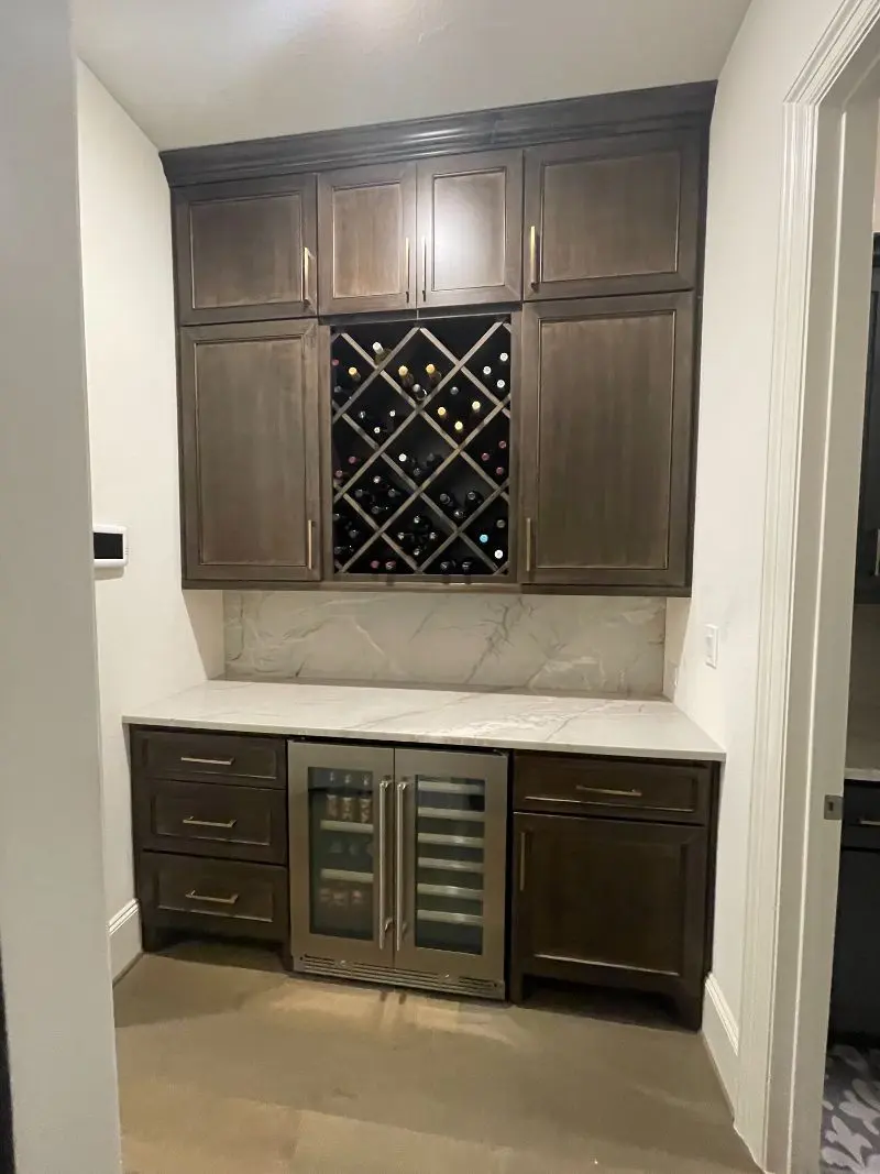 Wine bar with quartz countertop wine rack built-in cooler and dark wood cabinets in League City TX