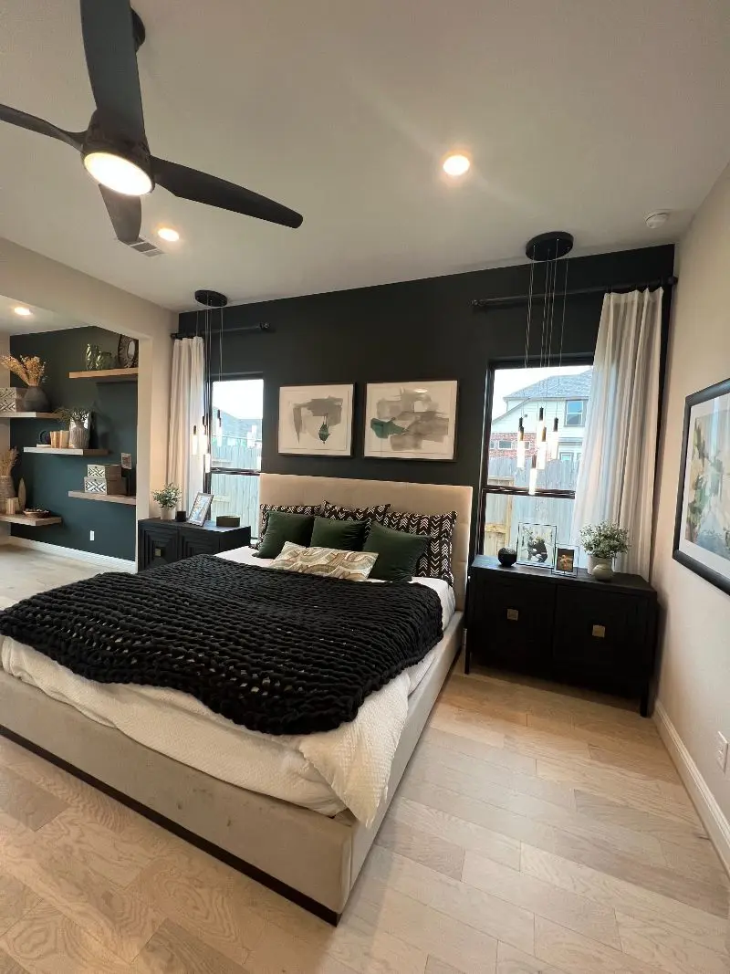 Modern master bedroom with dark green accent wall floating shelves and pendant lights in Alvin TX