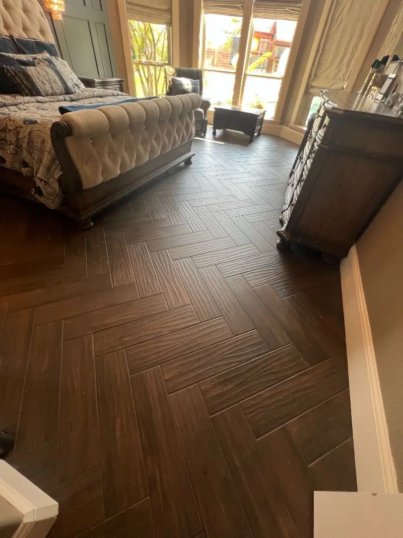 Herringbone wood-look tile flooring in luxury master bedroom with bay windows in Pearland TX