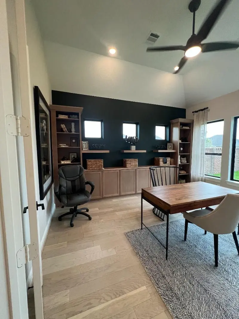 Home office with custom built-in cabinets dark accent wall and floating shelves in League City TX