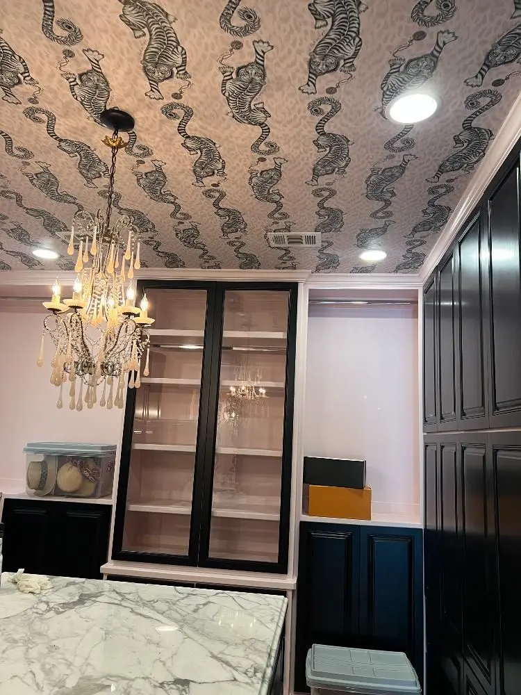 Luxury kitchen with marble island tiger wallpaper ceiling crystal chandelier and dark cabinets in Manvel TX