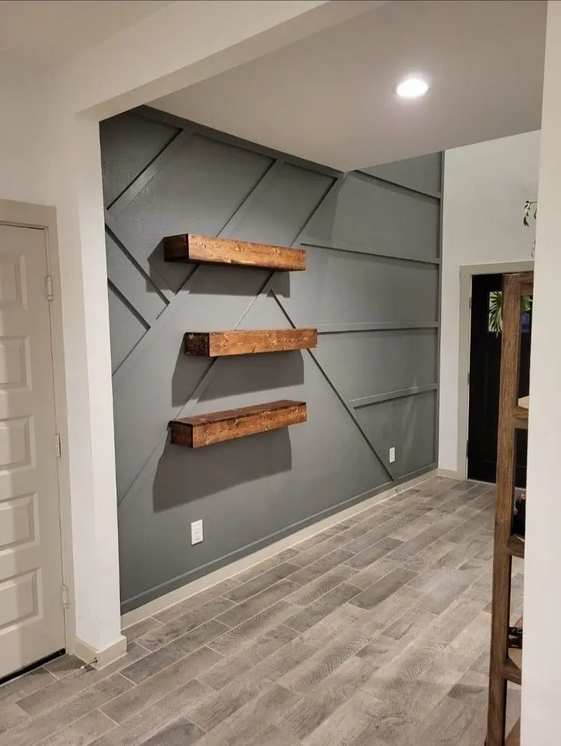 Geometric accent wall with rustic floating wood shelves and wood-look tile flooring in Dickinson TX